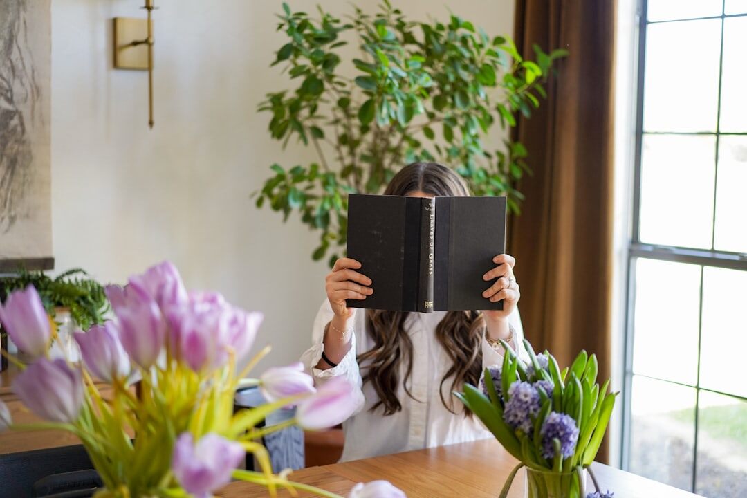 Brazilian woman reading a book curled up on a sofa at home
